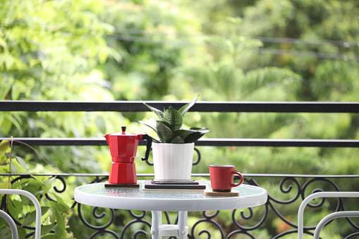 red coffee cup and red moka pot on glass table outdoor balcony