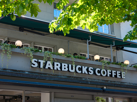 Bern, Switzerland - July 6 2022: Starbucks logo displayed at the facade of a Starbuks store. Starbucks is an American multinational chain of coffeehouses and roastery reserves