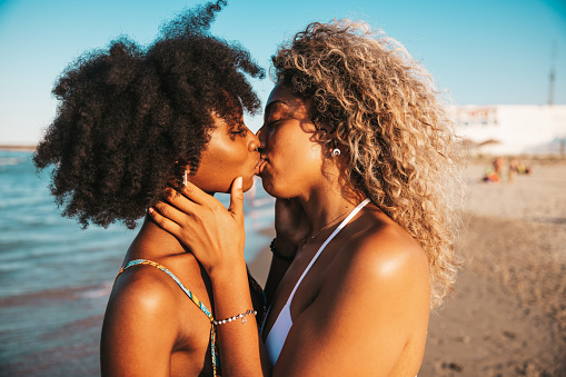 Cute and affectionate moments at sunset on the beach. On a vacation two people kissing at golden hour.