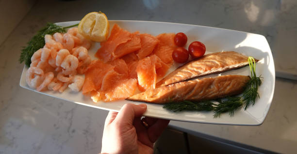 istock A hand serving a seafood platter on a white dish. 1411255080