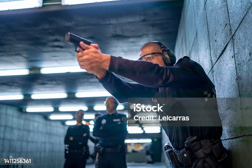 istock Police training in shooting gallery with short weapon. 1411256361