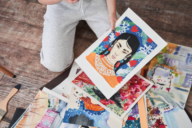 istock Female painter looking at her drawings while sitting at the floor during the weekend 1411256579