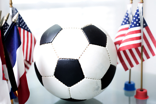 Soccer Ball on desk surrounded with many different flags from around the world in a classroom or office setting