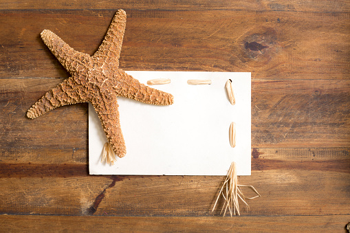 Large star fish accents a blank notecard on rough wooden background.