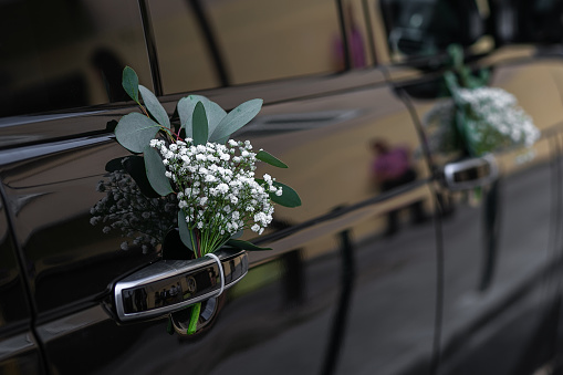 Wedding car decorated with flowers on the door.
