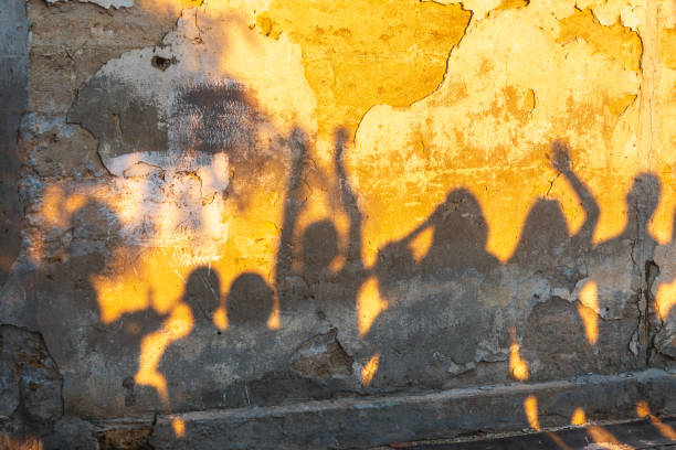 istock Shadows of dancing people on an old stone wall at sunset time. 1411267970