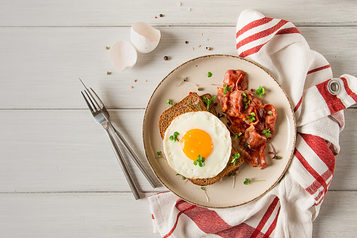 Breakfast, fried egg with bacon, micro-green, on a light background, no people, selective focus,