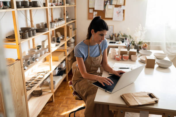 istock Female small business owner working on laptop from her modern pottery studio 1411271513
