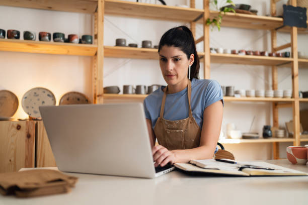 istock Female small business owner working on laptop from her modern pottery studio 1411271538