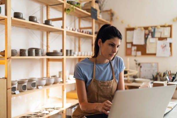 istock Female small business owner working on laptop from her modern pottery studio 1411271559