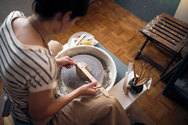 Female artisan measuring a clay pot in her pottery workshop Female artisan measuring a clay pot in her pottery workshop. homemade pottery wheel stock pictures, royalty-free photos & images