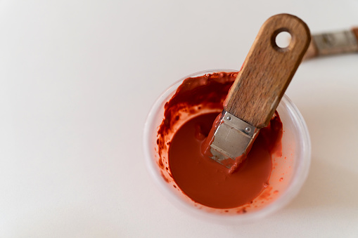 Close up of pottery bowl, with red paint and paintbrush