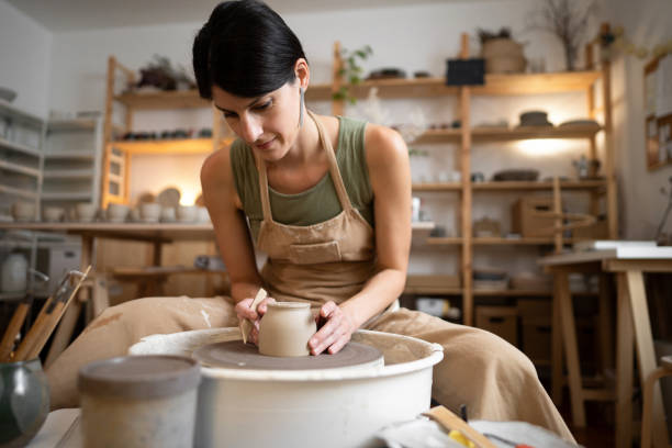 istock Female ceramics maker or potter working with pottery wheel in workshop 1411272634