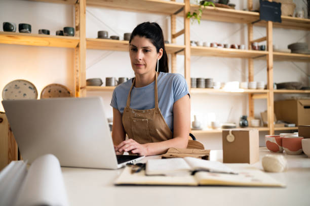 istock Female small business owner working on laptop from her modern pottery studio 1411272649