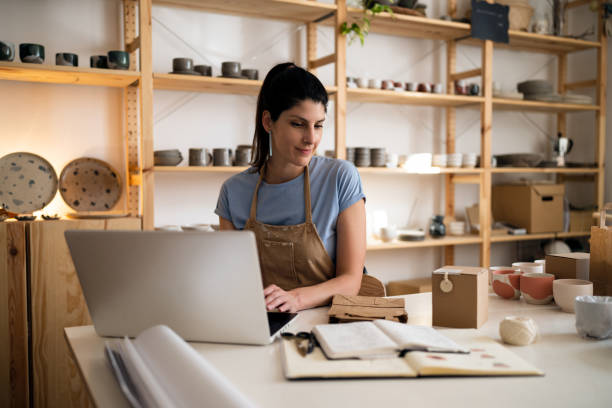 istock Female small business owner working on laptop from her modern pottery studio 1411272650
