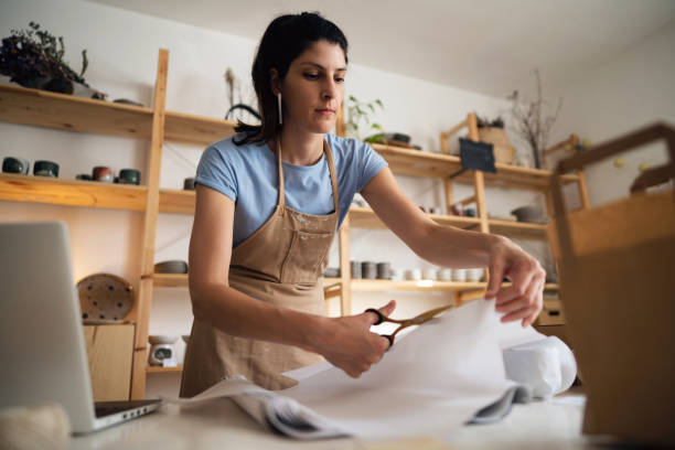 istock Female small business owner, cutting paper with scissors 1411272678