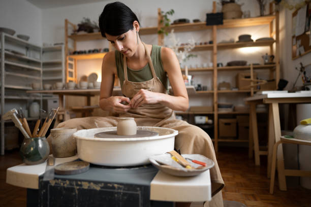 istock Female ceramics maker or potter working with pottery wheel in workshop 1411272708