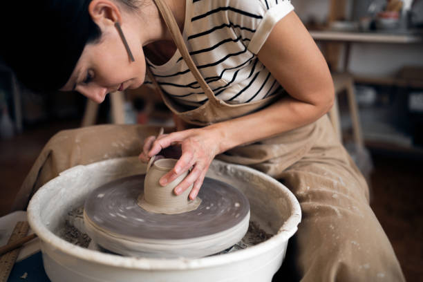 istock Young Caucasian woman working with a pottery wheel in her workshop 1411272743