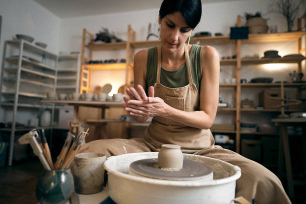 istock Female ceramics maker or potter working with pottery wheel in workshop 1411272841