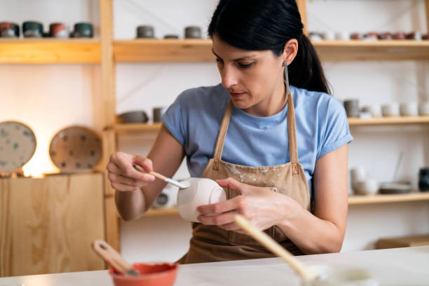 istock Female potter, painting pottery product in her workshop 1411272855