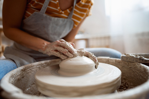 Caucasian female potter, working on pottery wheel, at her modern workshop
