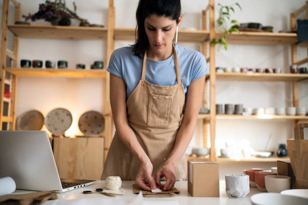 istock Female small business owner, using recyclable material for pottery packaging 1411272998