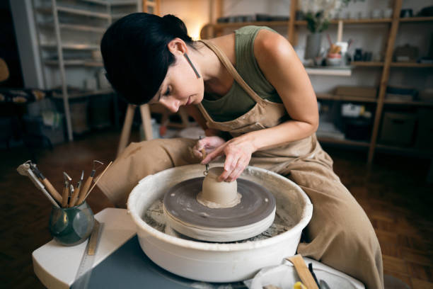 istock Female ceramics maker or potter working with pottery wheel in workshop 1411273028