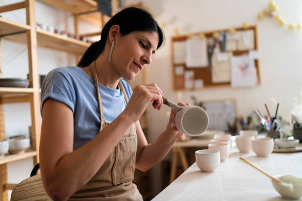 istock Female potter, painting pottery product in her workshop 1411273092