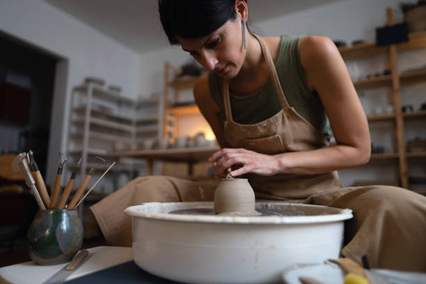 istock Female ceramics maker or potter working with pottery wheel in workshop 1411273160