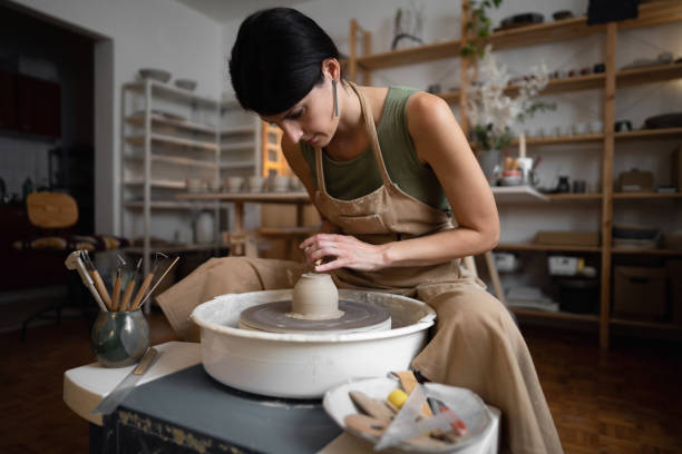 istock Female ceramics maker or potter working with pottery wheel in workshop 1411273161