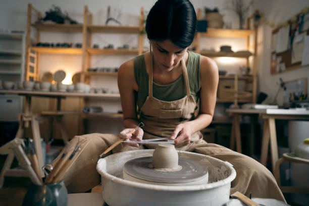 istock Female ceramics maker or potter working with pottery wheel in workshop 1411273165