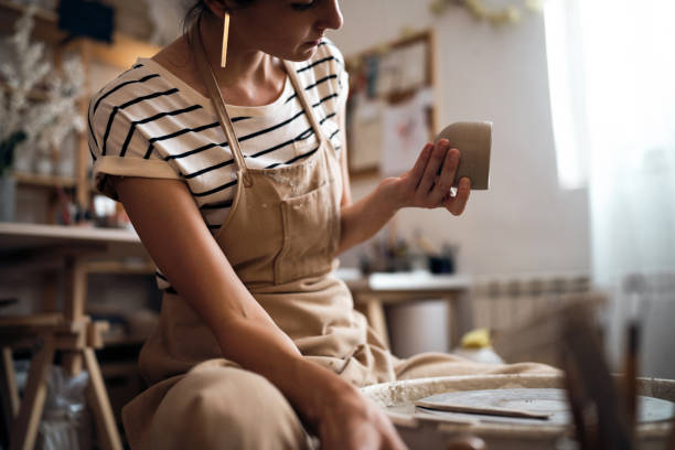 istock Female ceramics maker examining a finished clay pot 1411273166