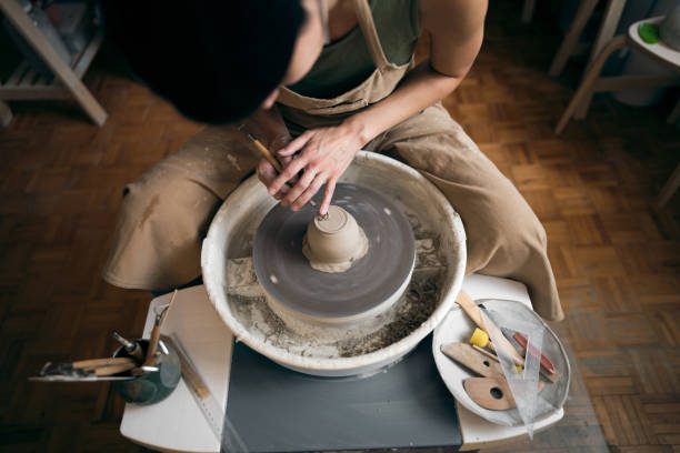 istock Female ceramics maker or potter working with pottery wheel in workshop 1411273167