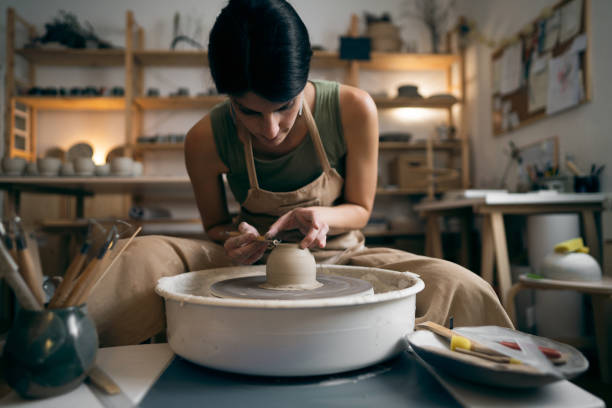 istock Female ceramics maker or potter working with pottery wheel in workshop 1411273180