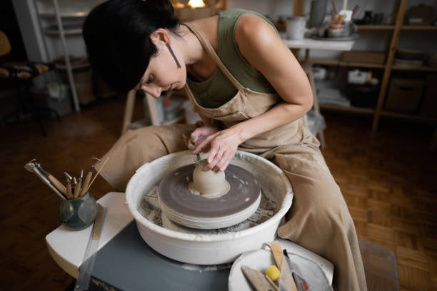 istock Female ceramics maker or potter working with pottery wheel in workshop 1411273829