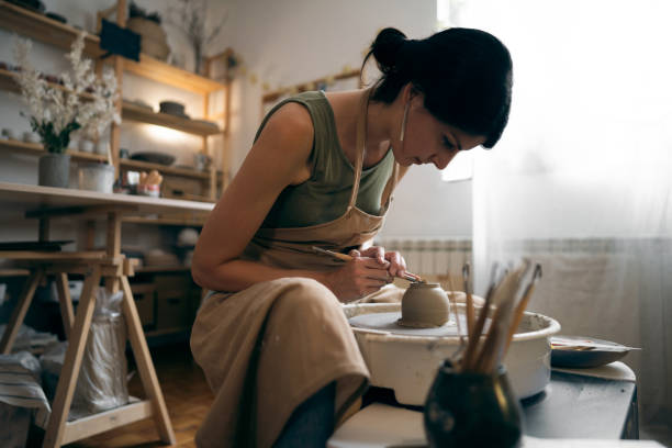istock Female ceramics maker or potter working with pottery wheel in workshop 1411273928