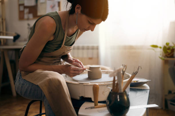 istock Female ceramics maker or potter working with pottery wheel in workshop 1411274511