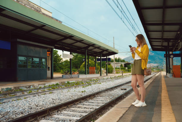istock Woman with smartphone is waiting for her train. 1411274639