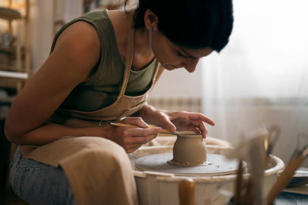 istock Female ceramics maker or potter working with pottery wheel in workshop 1411274655
