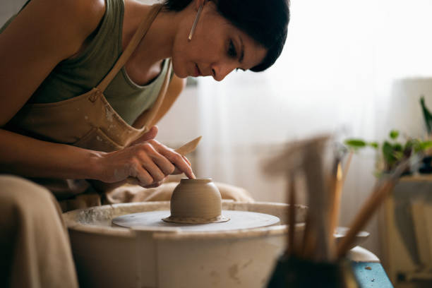 istock Female ceramics maker or potter working with pottery wheel in workshop 1411274746