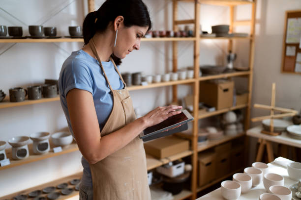 istock Female small business owner working on digital tablet from her pottery studio 1411275293