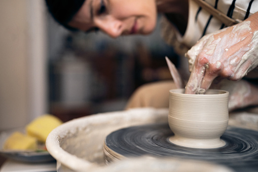 Close-up shot of young woman working with a pottery wheel in her workshop.
