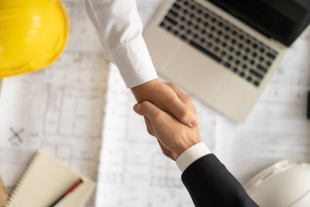 istock Customers and architects, building contractors join hands to congratulate them on agreeing to enter into a construction contract to participate in engineering design and construction. 1411275672