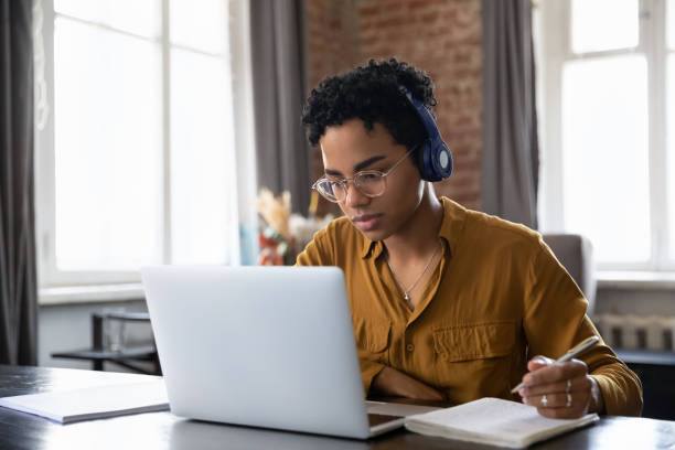 African woman studying listen audio course through wireless headphones
