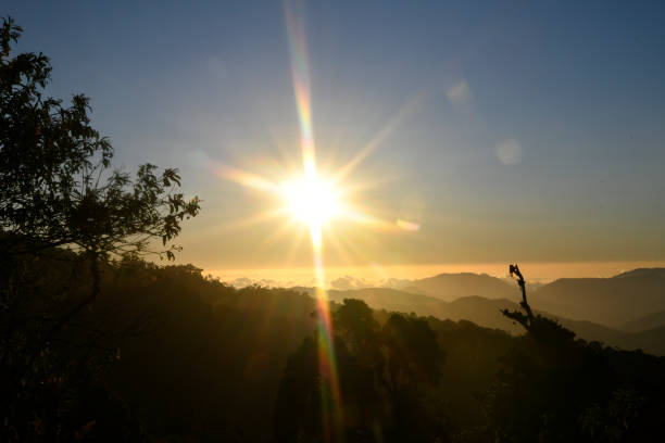 A sunset in the mountains over the clouds.  The sun is setting over the mountains.  The mountains are located above the clouds, which can be seen in the background.  The colors are not as dramatic due to the altitude but the sunset is still very pretty.