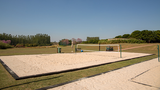 Singapore, Singapore - September, 6th 2012: An Asian couple is playing beach volleyball on beach on Sentosa Island. In background is small island with palm trees. At left side is walking a man.