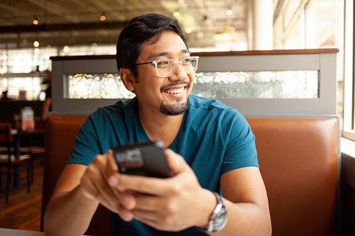 Man at a restaurant holding his smart phone 

Shallow DOF