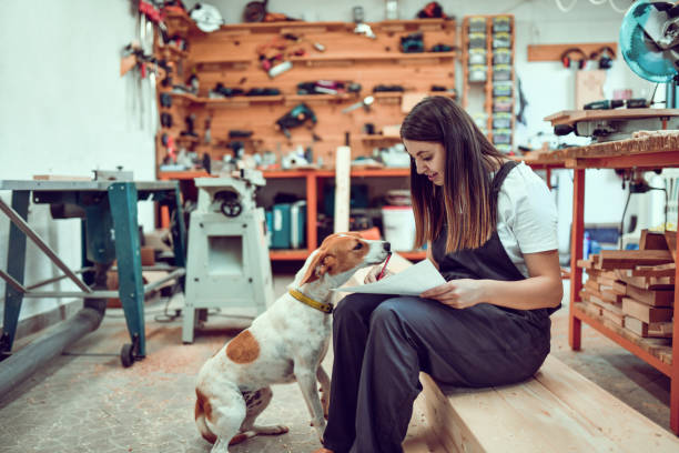 istock Female Woodwork Designer Trying To Pet Puppy And Complete Project At Same Time 1411284586