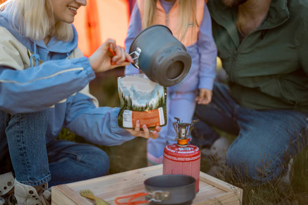 Couple with little girl cooking dried-food for hiking at campsite Young couple with little girl cooking dried-food for hiking, pouring boiling water into the package. Family at campsite making food for travelers. Sublimated food and family camping concept girls getting ready to go out stock pictures, royalty-free photos & images