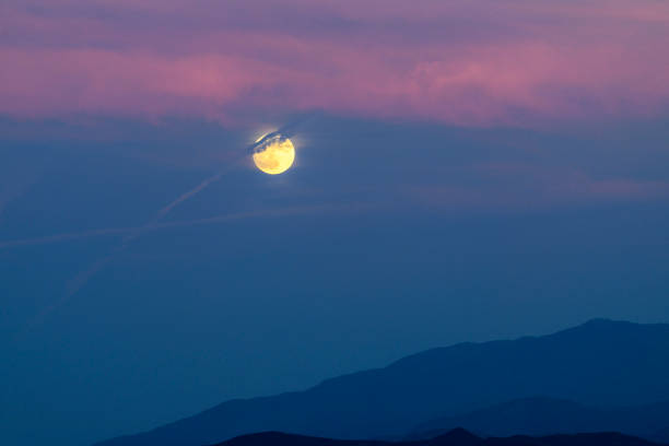 istock Full moon rises behind mountains with colorful sky at sunset 1411285161